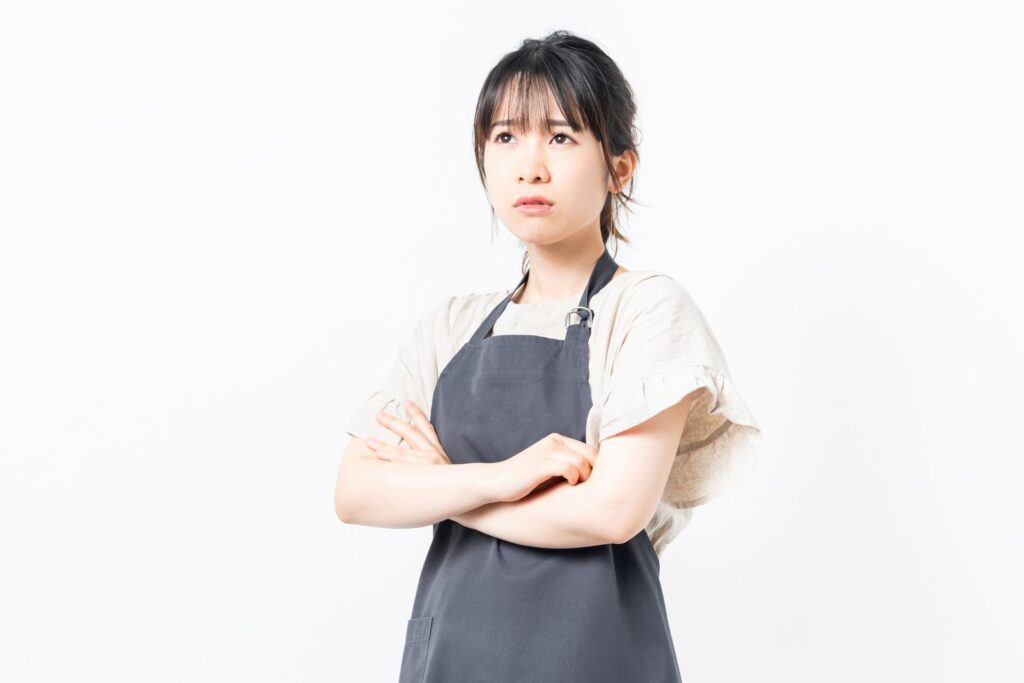 洗濯物の干し方に悩むエプロン姿の女性の画像