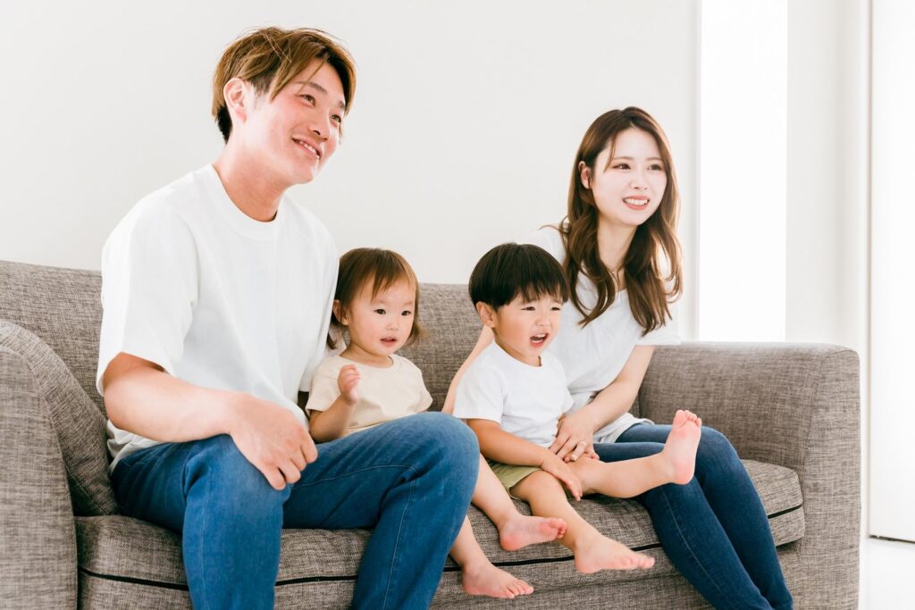 リビングのソファに座る4人家族の画像