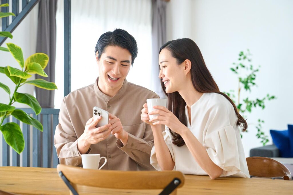 スマホで住宅情報を確認する夫婦の画像