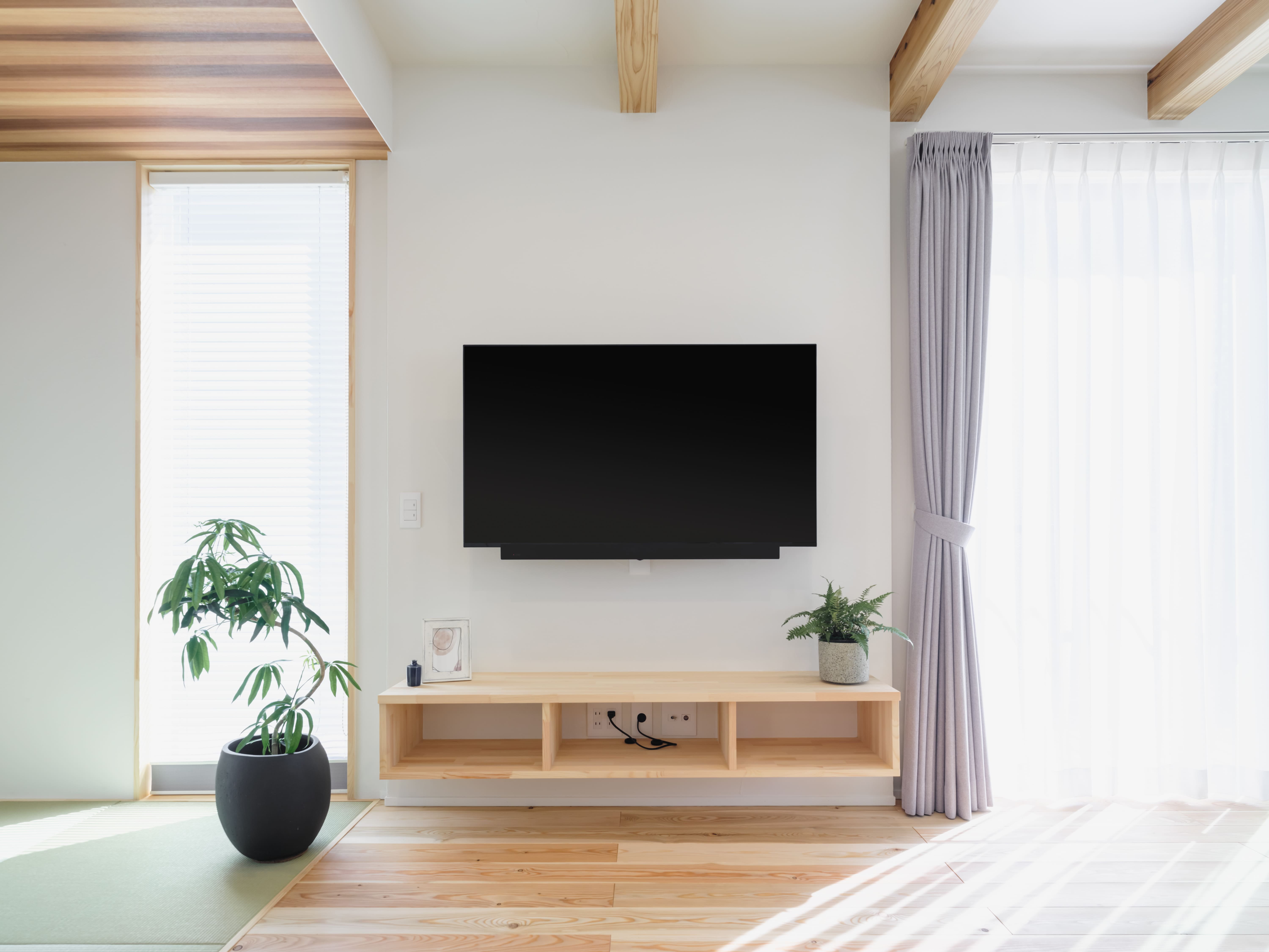 壁掛けテレビと木製のコンソール。配線が隠れすっきりしたリビング